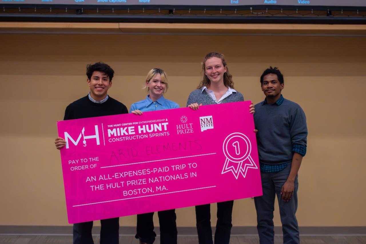 Four people holding an oversized check